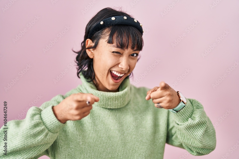 Young beautiful woman standing over pink background pointing fingers to camera with happy and funny face. good energy and vibes. Young beautiful woman standing over pink background pointing fingers to camera with happy and funny face. good energy and vibes.