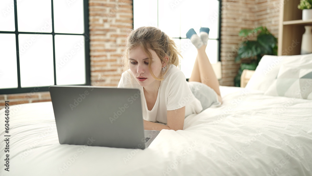 Young blonde woman using laptop lying on bed at bedroom Young blonde woman using laptop lying on bed at bedroom