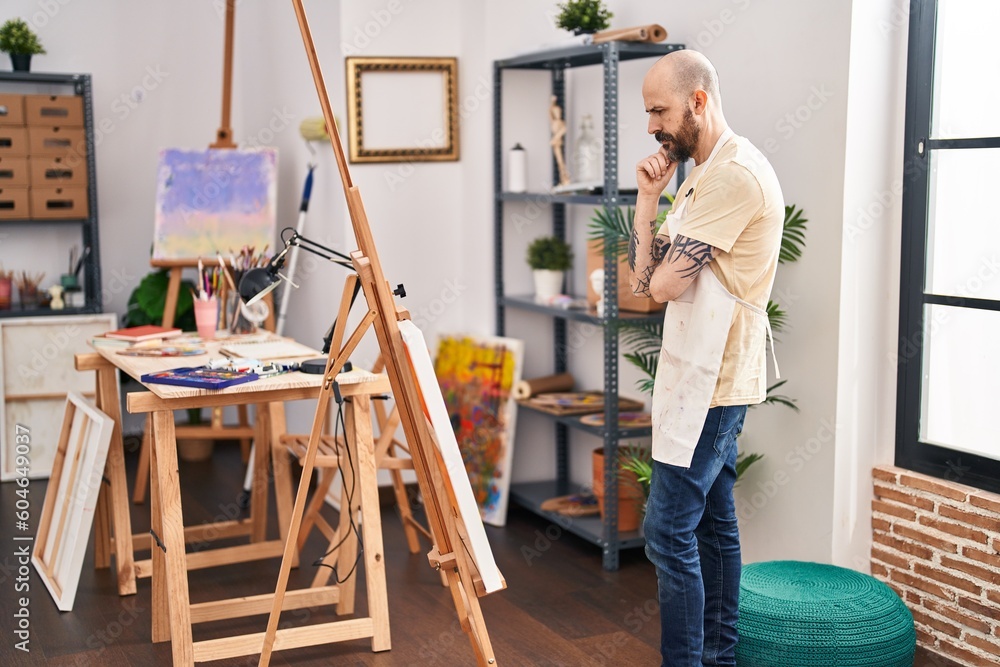 Young bald man artist looking draw with serious expression at art studio Young bald man artist looking draw with serious expression at art studio