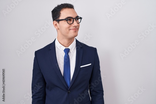 Young hispanic man wearing suit and tie smiling looking to the side and staring away thinking.