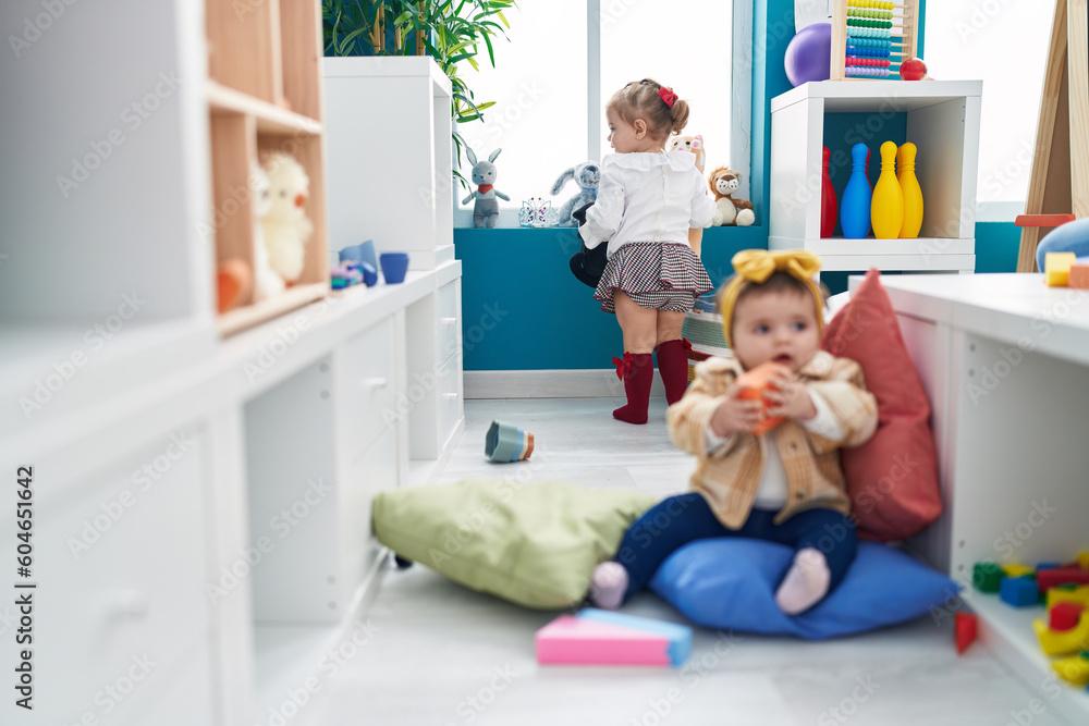 Fototapeta premium Adorable girls sitting on floor playing at kindergarten