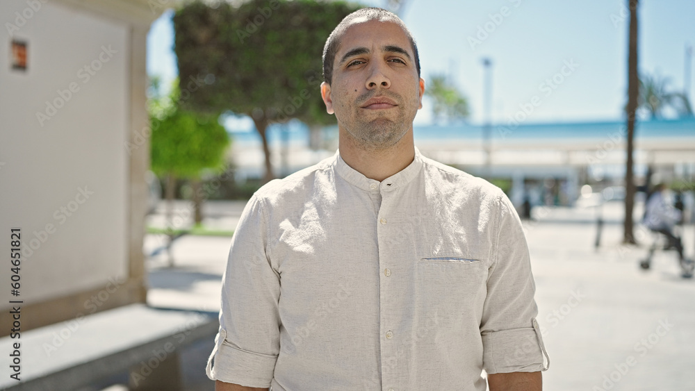 Obraz premium Young hispanic man standing with serious expression at street