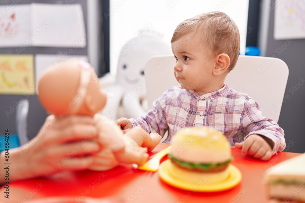 Adorable caucasian boy playing with baby doll and food toy at kindergarten Adorable caucasian boy playing with baby doll and food toy at kindergarten