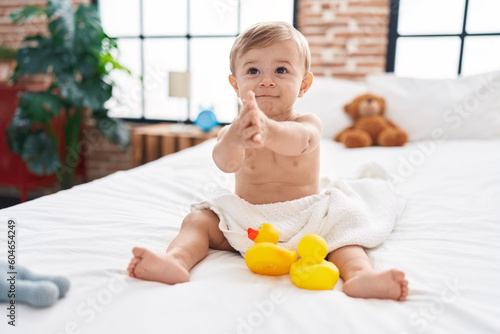 Adorable caucasian boy sitting on bed clapping hands at bedroom