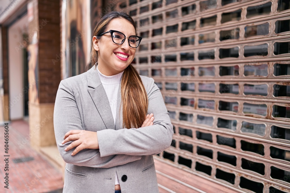 Young beautiful hispanic woman business worker smiling confident standing with arms crossed gesture at street