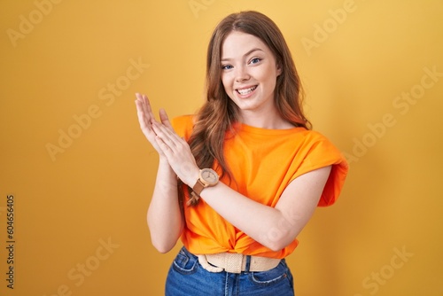 Caucasian woman standing over yellow background clapping and applauding happy and joyful  smiling proud hands together
