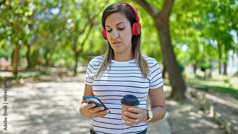 Middle eastern woman using smartphone wearing headphones at park