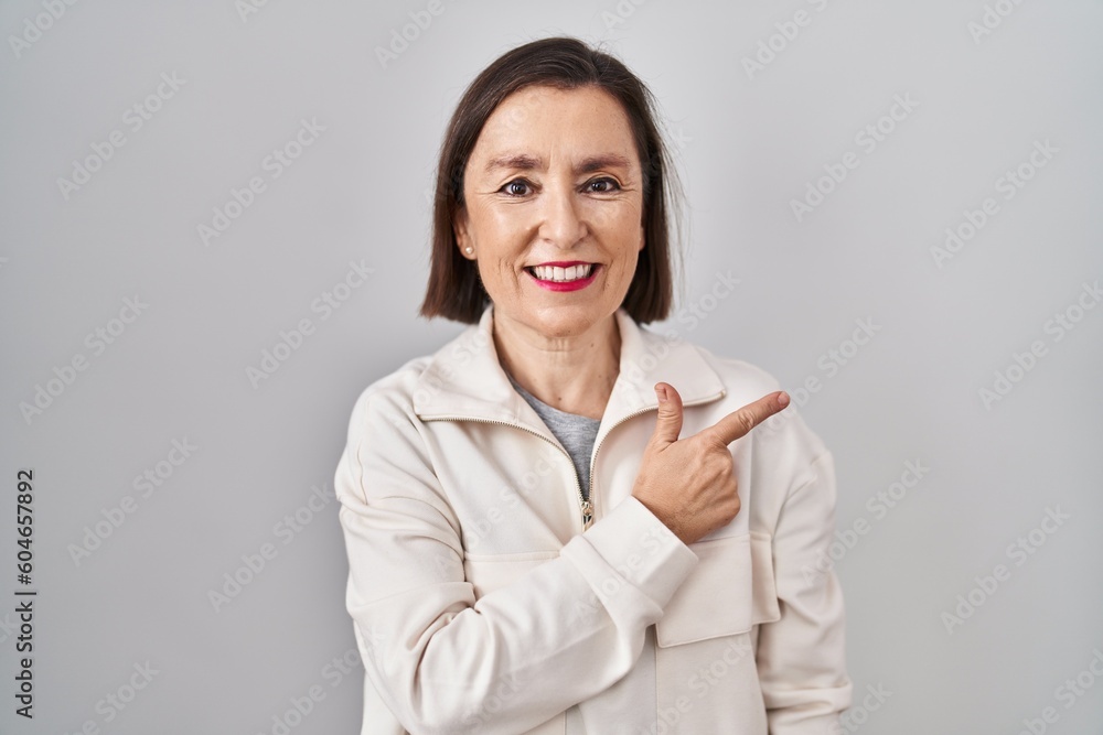 Middle age hispanic woman standing over isolated background cheerful with a smile on face pointing with hand and finger up to the side with happy and natural expression Middle age hispanic woman standing over isolated background cheerful with a smile on face pointing with hand and finger up to the side with happy and natural expression
