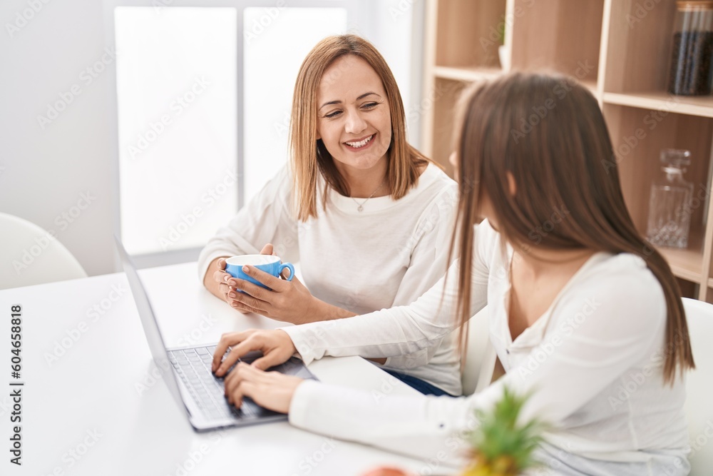 Two women mother and daughter using laptop drinking coffee at home Two women mother and daughter using laptop drinking coffee at home