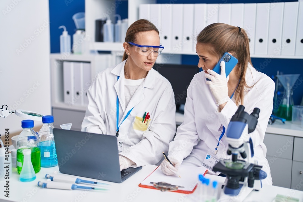 Two women scientists talking on the smartphone working at laboratory Two women scientists talking on the smartphone working at laboratory