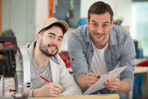 two male workers in workshop with circular saw