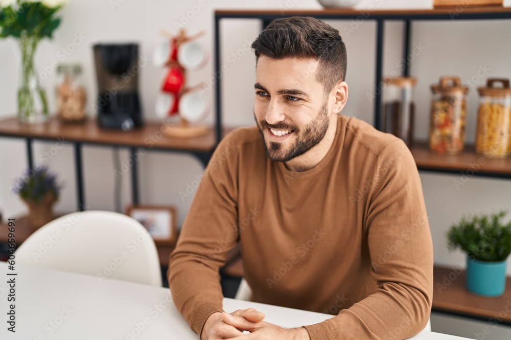Young hispanic man smiling confident sitting on table at home Young hispanic man smiling confident sitting on table at home