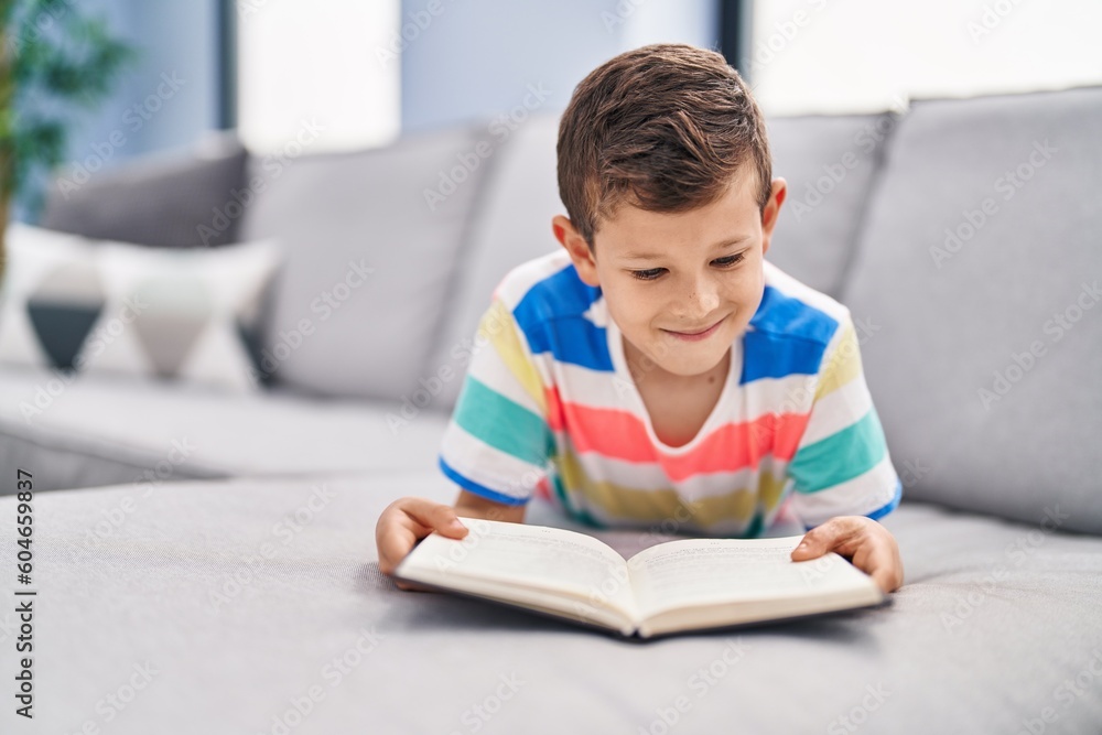 Blond child reading book sitting on sofa at home Blond child reading book sitting on sofa at home