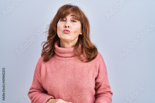 Middle age hispanic woman standing over isolated background looking at the camera blowing a kiss on air being lovely and sexy. love expression.