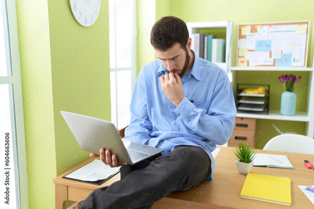 Young hispanic man business worker using laptop with doubt expression at office Young hispanic man business worker using laptop with doubt expression at office