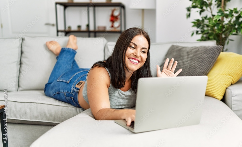 Young beautiful hispanic woman having video call lying on sofa at home Young beautiful hispanic woman having video call lying on sofa at home