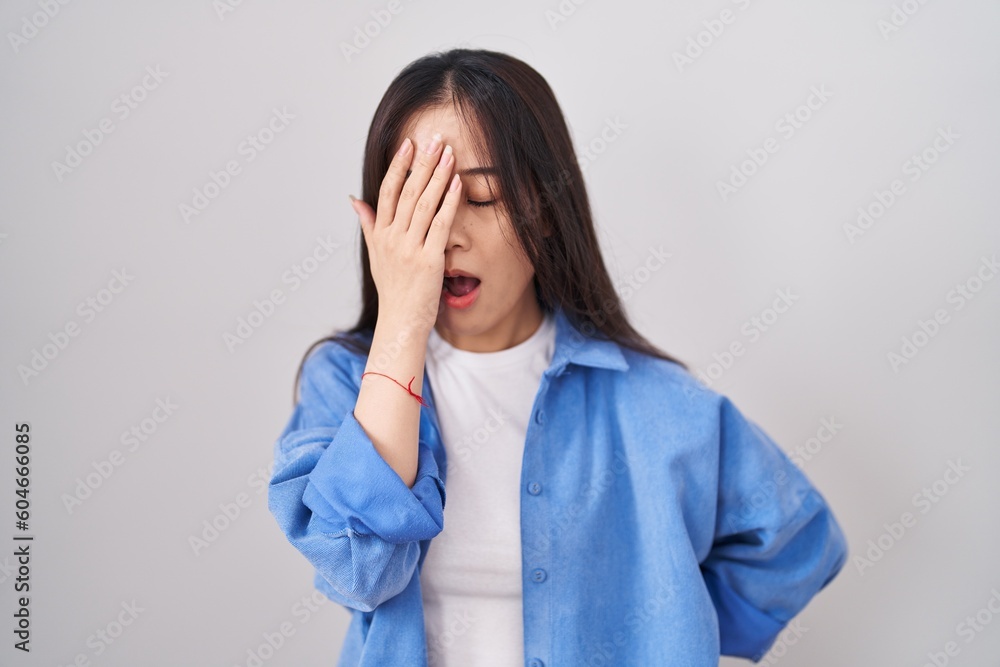 Young chinese woman standing over white background yawning tired covering half face, eye and mouth with hand. face hurts in pain. Young chinese woman standing over white background yawning tired covering half face, eye and mouth with hand. face hurts in pain.