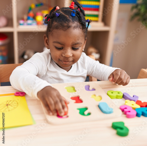 Obraz na płótnie African american girl playing with maths puzzle game sitting on table at kinderg