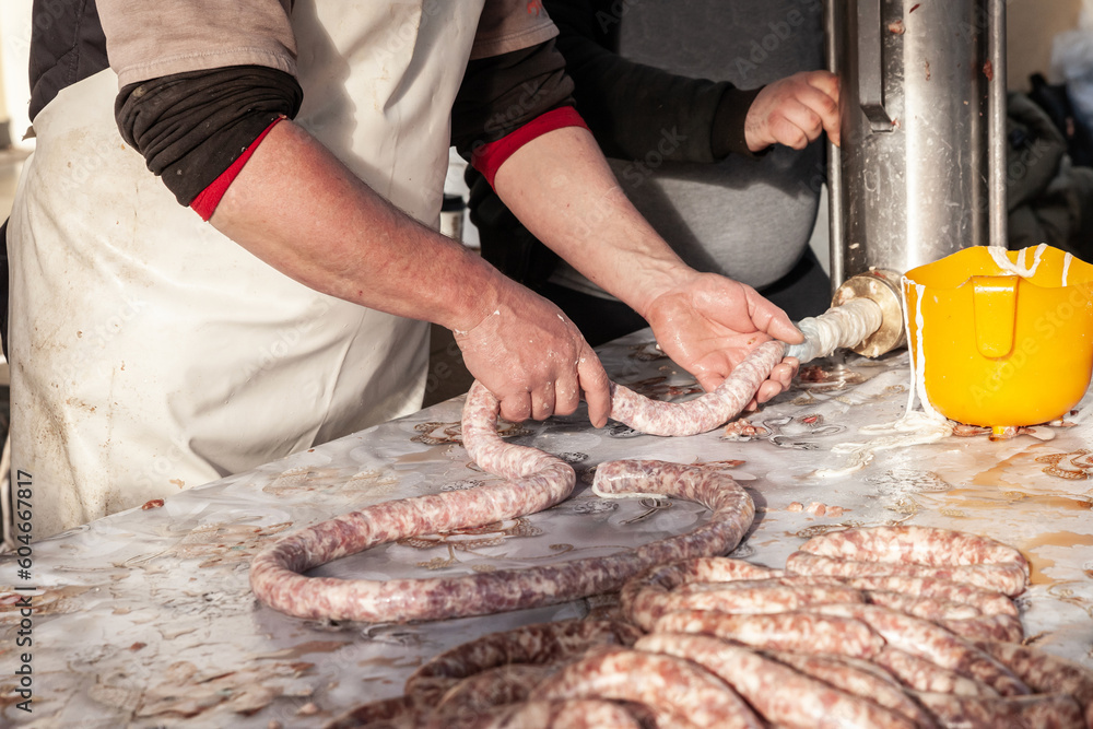 Selective blur on a sausage machine with hands of male people, butchers, making sausages in the countryside of Serbia. Sausage, or Kobasica, is a traditional food from Balkans.