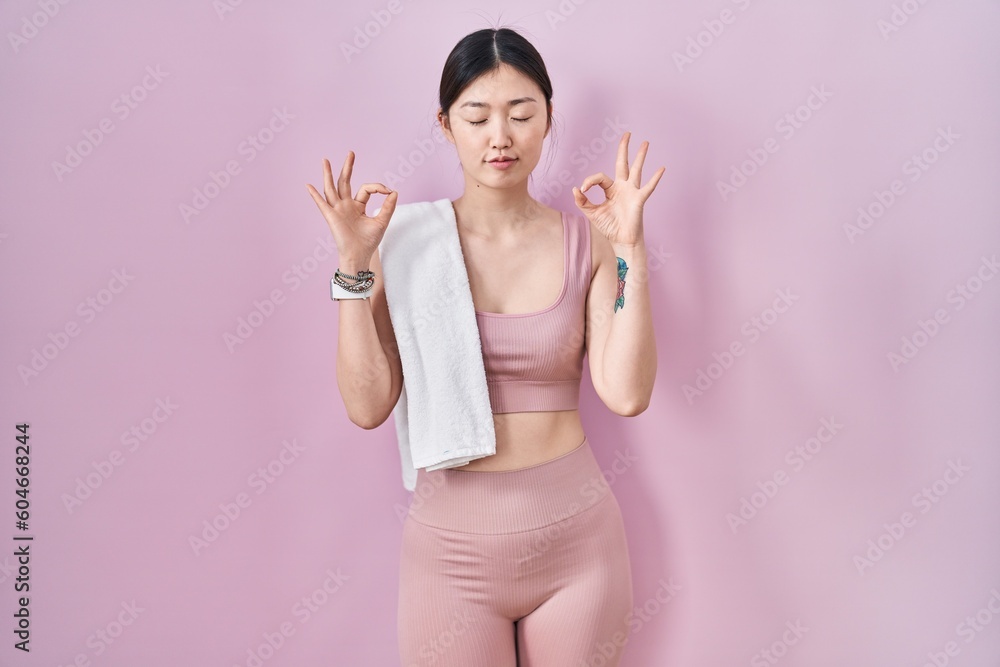 Chinese young woman wearing sportswear and towel relaxed and smiling with eyes closed doing meditation gesture with fingers. yoga concept. Chinese young woman wearing sportswear and towel relaxed and smiling with eyes closed doing meditation gesture with fingers. yoga concept.