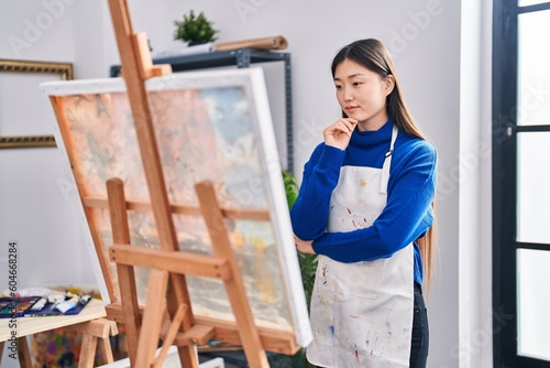 Chinese woman artist looking draw with doubt expression at art studio