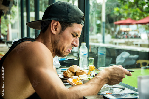 Unhappy young man eating food in a cafe photo