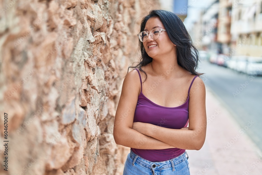 Young chinese woman standing with arms crossed gesture at street Young chinese woman standing with arms crossed gesture at street