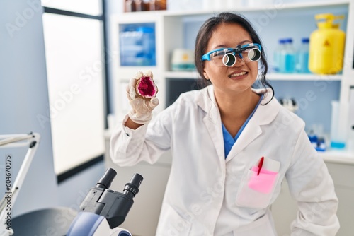 Young chinese woman wearing scientist uniform examining geode at laboratory