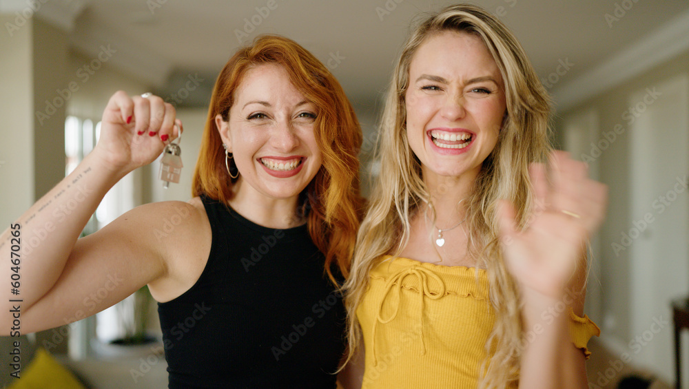 Two women smiling confident holding key of new home at home Two women smiling confident holding key of new home at home