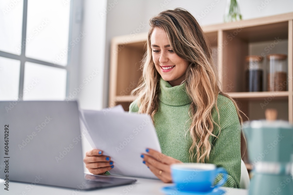 Young woman reading document using laptop at home Young woman reading document using laptop at home