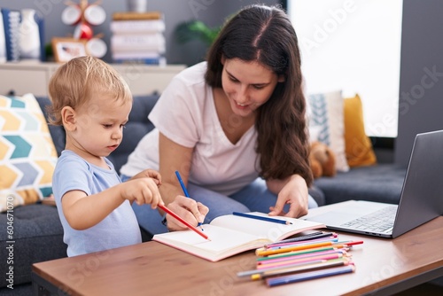 Mother and son sitting on sofa drawing on notebook at home