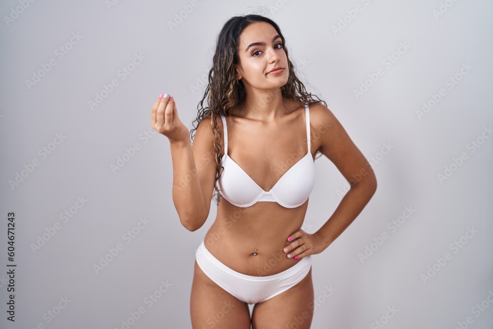 Young hispanic woman wearing white lingerie doing italian gesture with hand and fingers confident expression Young hispanic woman wearing white lingerie doing italian gesture with hand and fingers confident expression