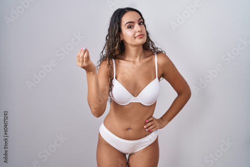 Young hispanic woman wearing white lingerie doing italian gesture with hand and fingers confident expression © Krakenimages.com