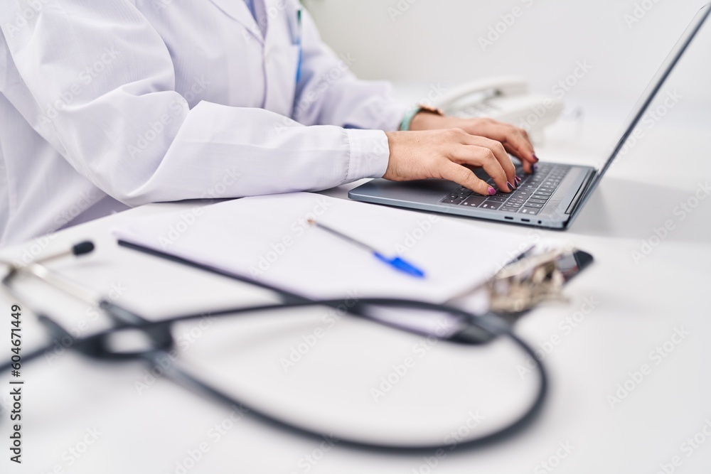 Young hispanic woman wearing doctor uniform using laptop working at clinic Young hispanic woman wearing doctor uniform using laptop working at clinic