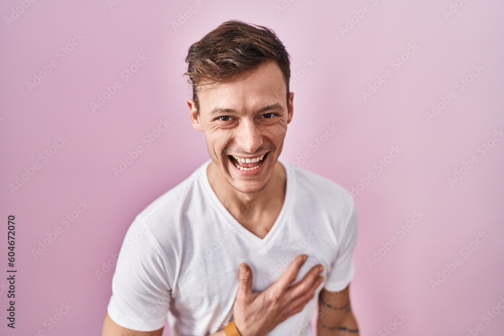 Caucasian man standing over pink background smiling and laughing hard out loud because funny crazy joke with hands on body. Caucasian man standing over pink background smiling and laughing hard out loud because funny crazy joke with hands on body.