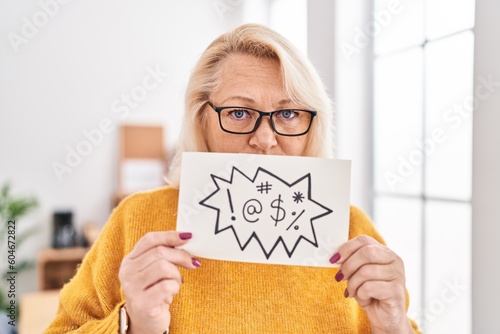 Middle age blonde woman business worker holding shooting message banner at office