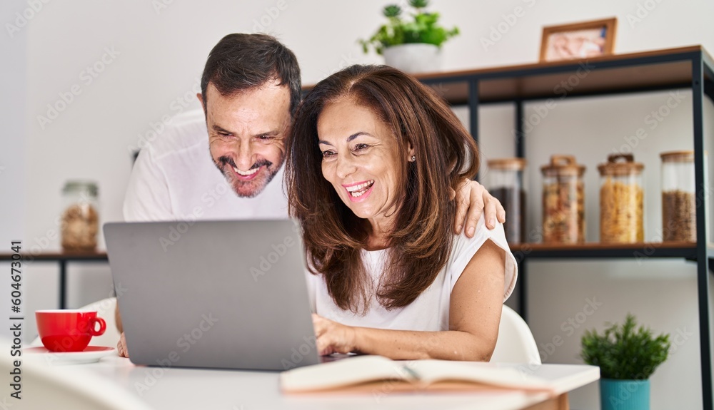 Middle age man and woman couple hugging each other working sitting on table at home Middle age man and woman couple hugging each other working sitting on table at home