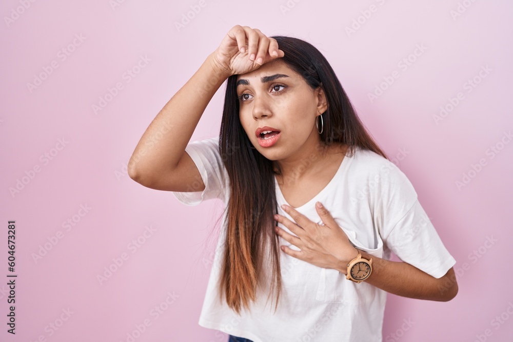 Young arab woman standing over pink background touching forehead for illness and fever, flu and cold, virus sick
