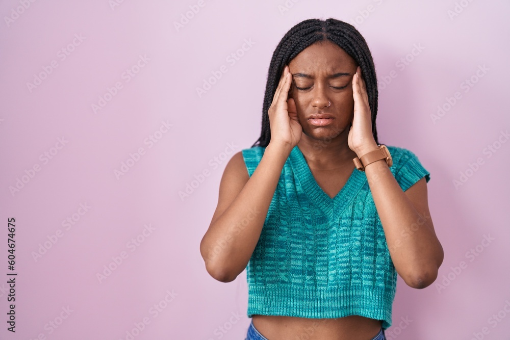 Young african american with braids standing over pink background with hand on head, headache because stress. suffering migraine. Young african american with braids standing over pink background with hand on head, headache because stress. suffering migraine.