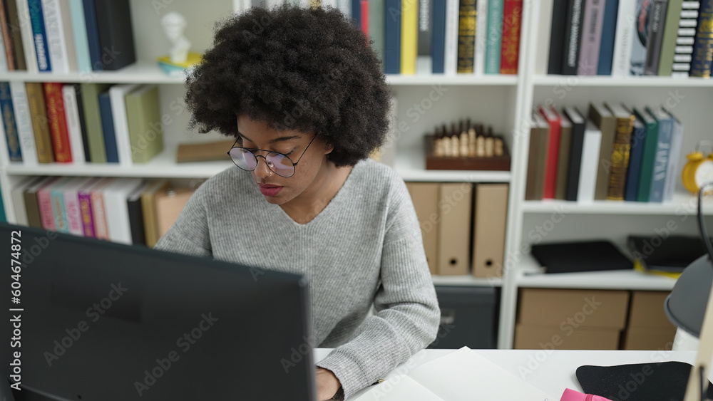 African american woman student using computer studying at library ...