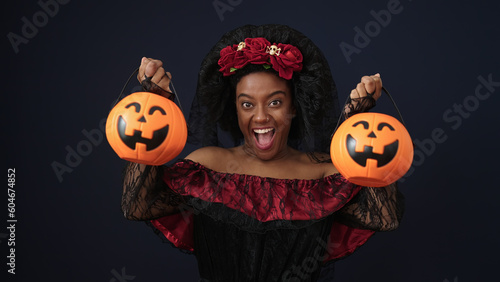 African american woman wearing katrina costume holding halloween pumpkin baskets over isolated black background