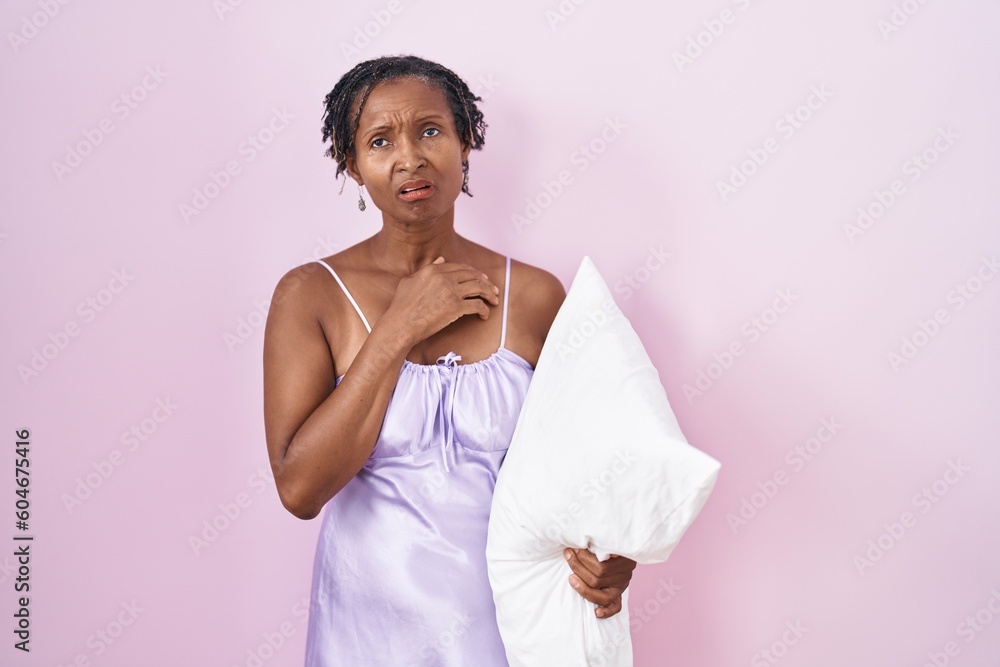 African woman with dreadlocks wearing pajama hugging pillow looking sleepy and tired, exhausted for fatigue and hangover, lazy eyes in the morning. African woman with dreadlocks wearing pajama hugging pillow looking sleepy and tired, exhausted for fatigue and hangover, lazy eyes in the morning.
