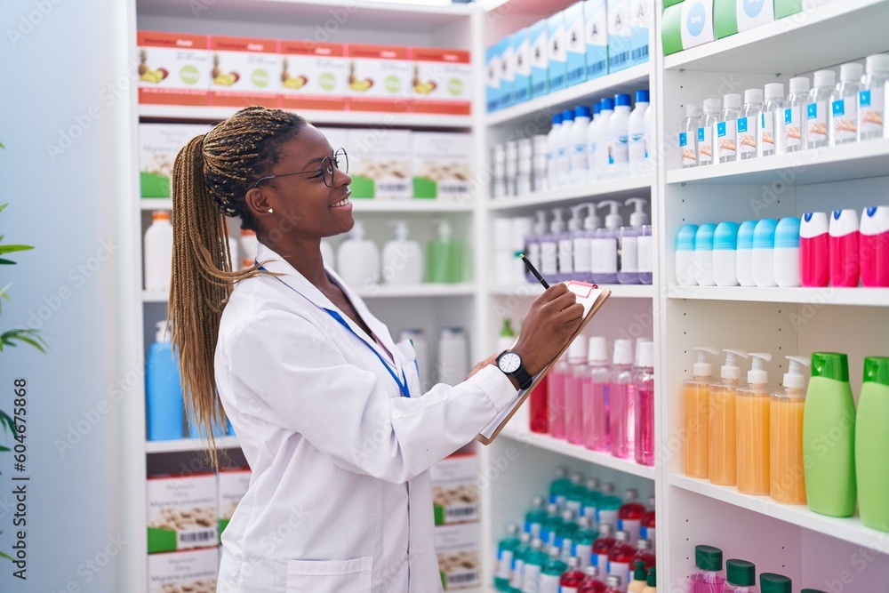 African american woman pharmacist writing on document at pharmacy