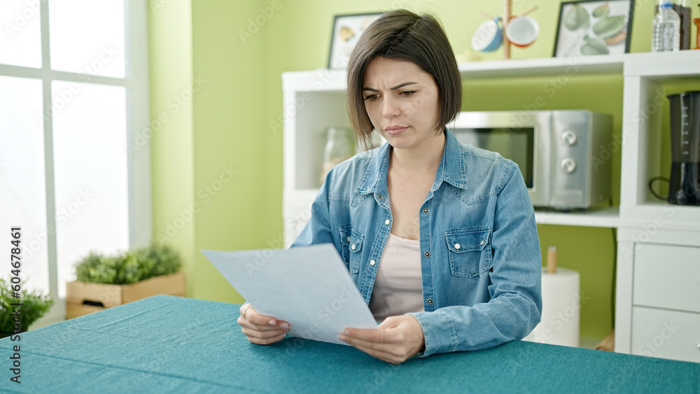 Young caucasian woman reading document sitting on table at home Young caucasian woman reading document sitting on table at home