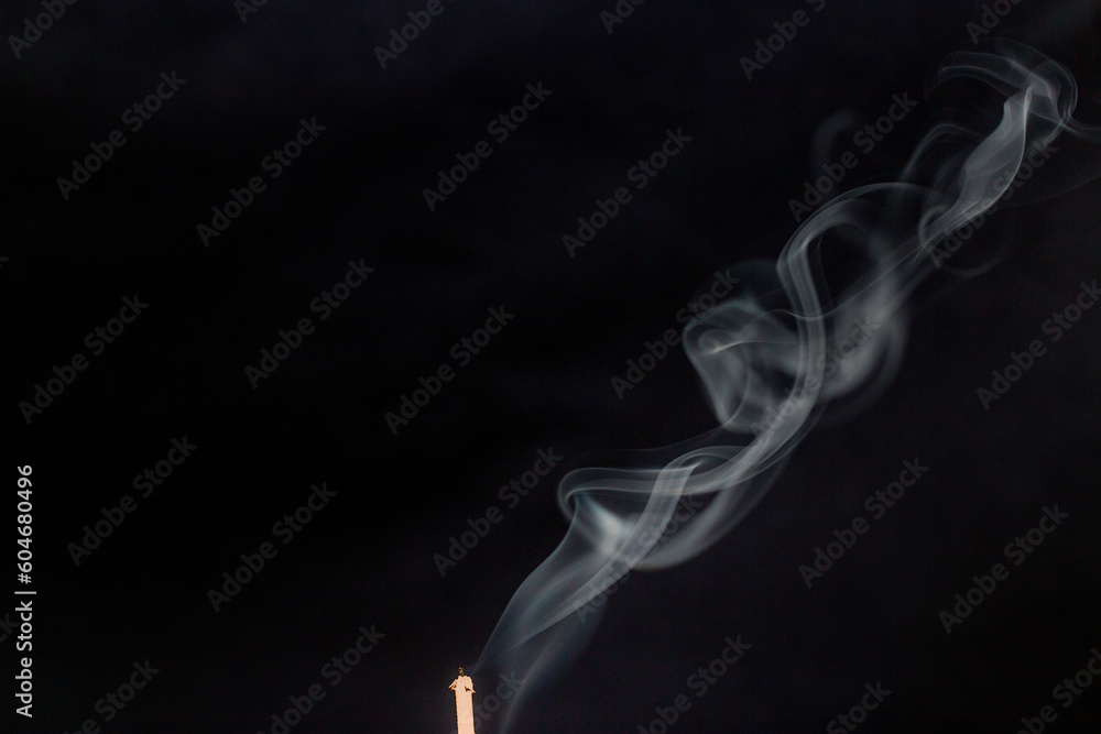 White smoke from incense wraps beautifully in the air on a dark background close-up White smoke from incense wraps beautifully in the air on a dark background close-up