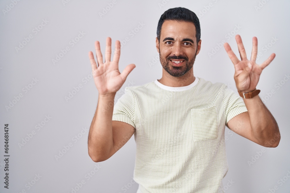 Hispanic man with beard standing over isolated background showing and pointing up with fingers number nine while smiling confident and happy. Hispanic man with beard standing over isolated background showing and pointing up with fingers number nine while smiling confident and happy.
