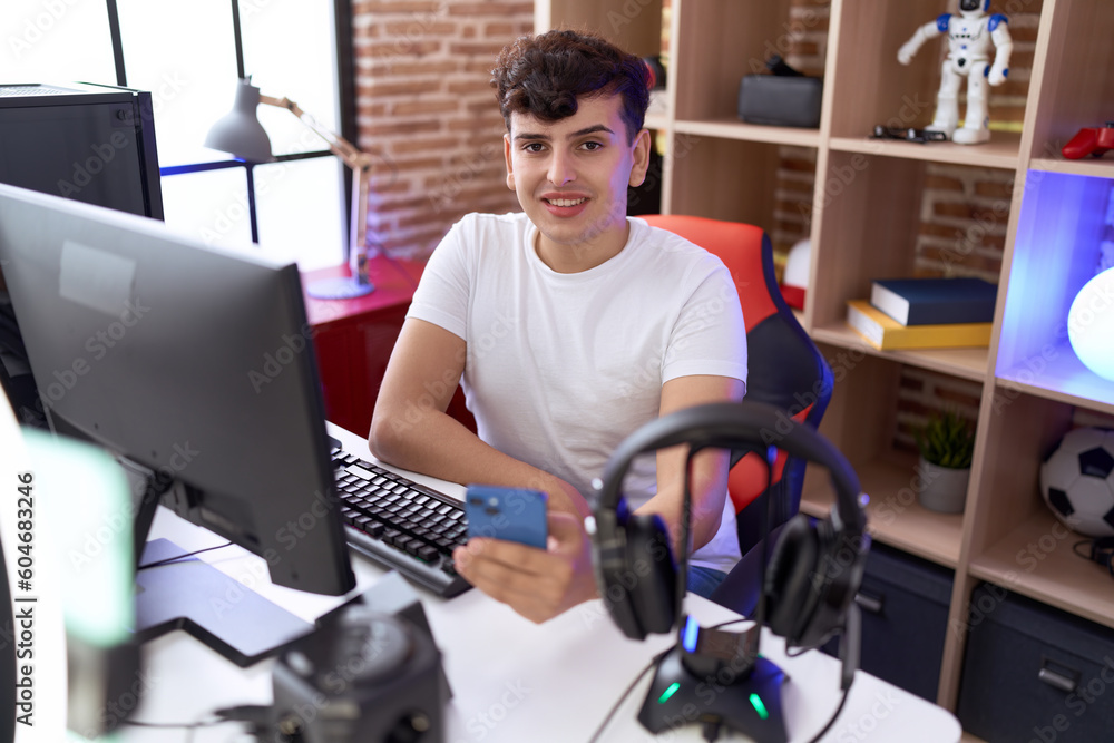Non binary man streamer using computer and smartphone at gaming room Non binary man streamer using computer and smartphone at gaming room