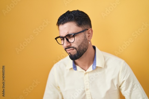 Hispanic young man wearing business clothes and glasses with hand on stomach because indigestion, painful illness feeling unwell. ache concept. © Krakenimages.com