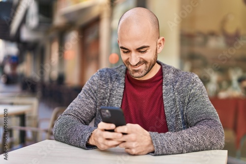 Young man smiling confident using smartphone at coffee shop terrace