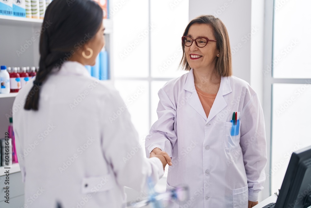 Two women pharmacist smiling confident shake hands at pharmacy Two women pharmacist smiling confident shake hands at pharmacy